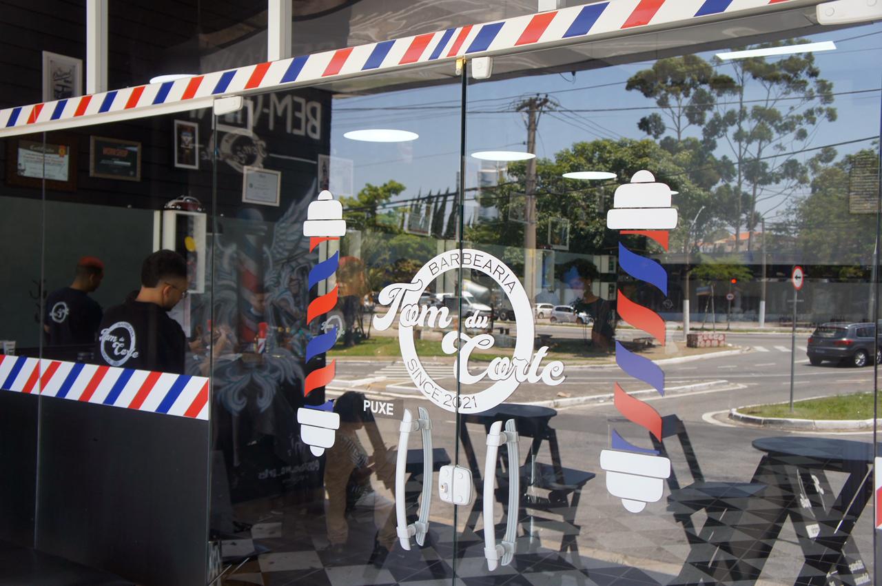 Vitrine da barbearia com barber poles e logo