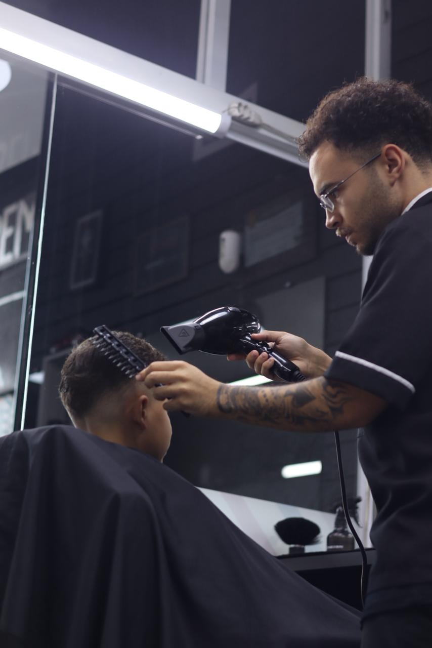 Barbeiro finalizando com secador em cliente na Tom du Corte