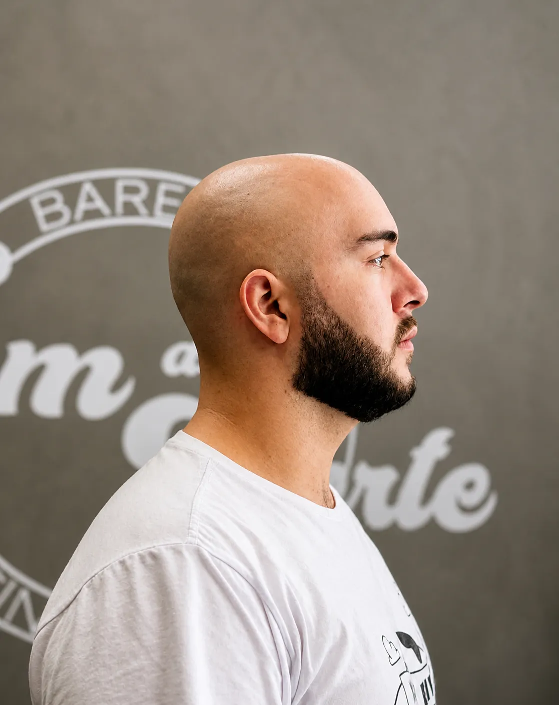 Cliente com barba alinhada em frente ao logo Tom du Corte