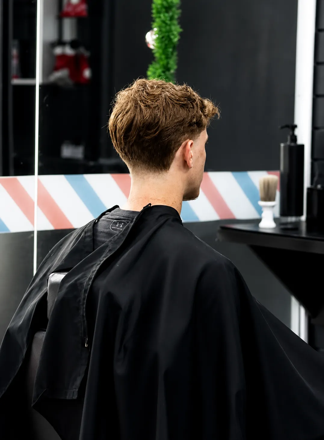 Cliente na cadeira diante do espelho da barbearia